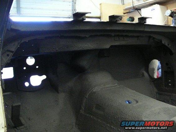 Interior of car with sound deadening applied to floor and firewall. Holes visible for pedals and steering column