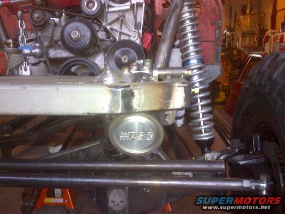 Close-up of Jeep CJ front suspension with engine parts and a "WARN" cap visible
