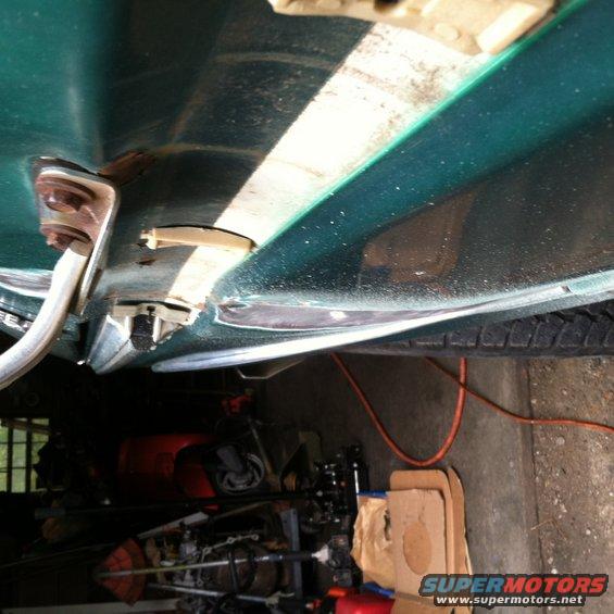 close-up of green vehicle's door frame, showing hinges and interior details