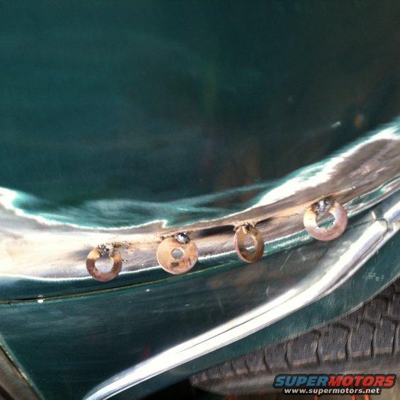 Close-up of rivets on a green car fender during restoration