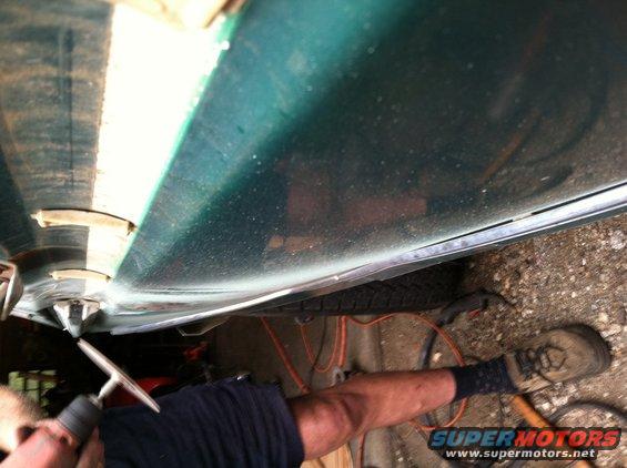 close-up of car door bottom, showing some rust and a tire underneath