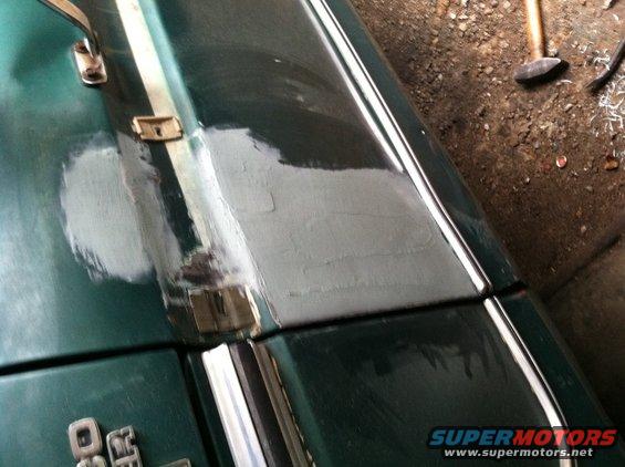 Green 1978 Ford Bronco hood panel with body filler and chrome trim, viewed from above