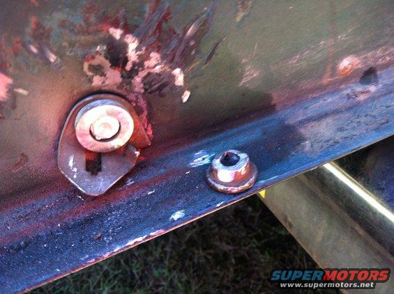 Close-up of a metal bracket with a bolt and a separate nut