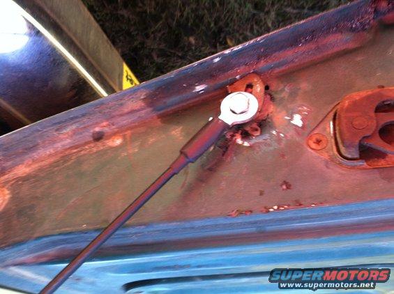 Close-up of rusted hood hinge mechanism on a blue vehicle