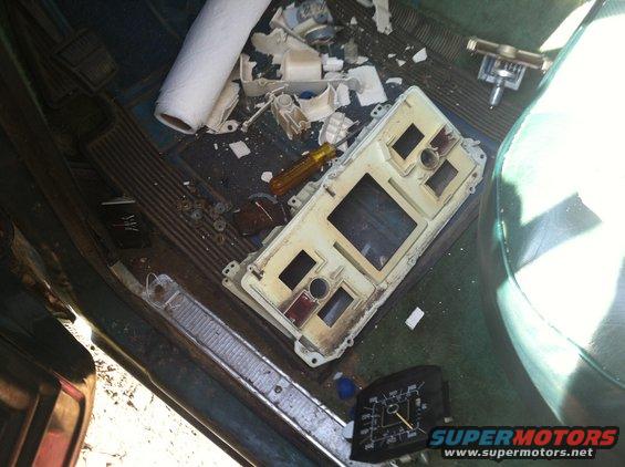 Disassembled dashboard cluster and roll of paper towels inside a vehicle interior