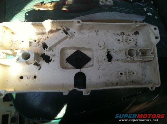 Back of a dirty gauge cluster housing with mounting points and connectors