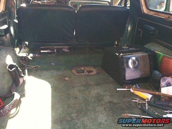 Interior view of a vehicle showing rear seats and a large black electronic device