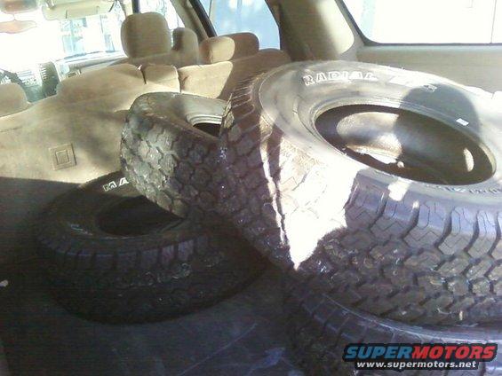Spare tires stacked in the cargo area of a vehicle. Text on tire reads RADIAL
