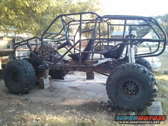 Custom buggy frame with large tires and exposed engine, viewed from the side