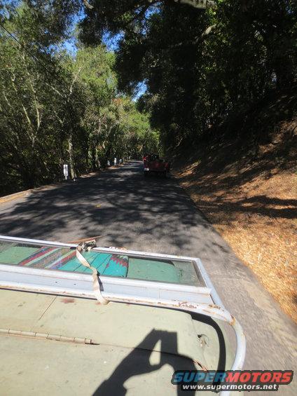 View from a trailer carrying a door, looking down a road with a red convertible ahead