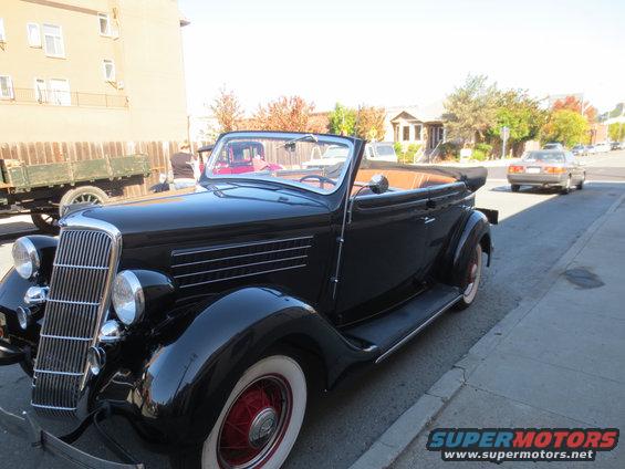 Black convertible automobile with whitewall tires and red wheels parked on a street