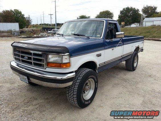 Two-tone blue and white 1994 Ford F-250 pickup truck with chrome bumper and grille, parked on dirt