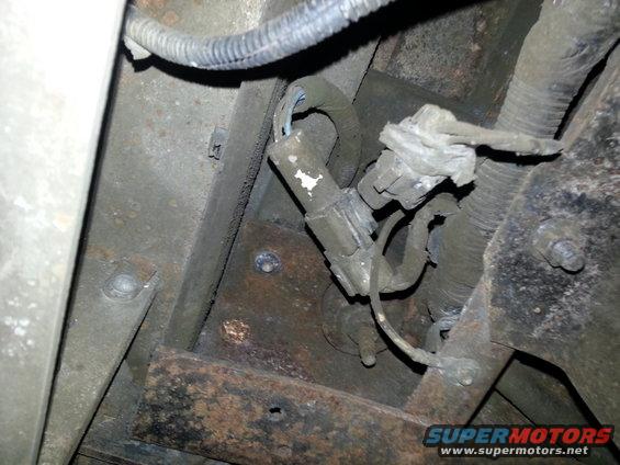 Undercarriage of a vehicle showing rusted metal frame, wiring harness, and electrical connectors
