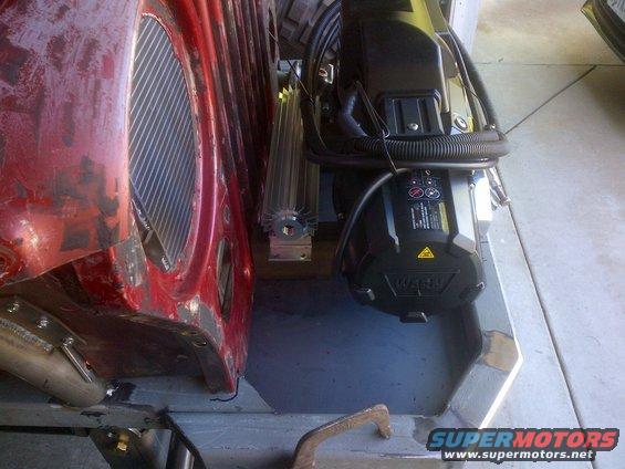 Close-up of a red Jeep CJ-series vehicle's engine bay with a new winch and cooler installed