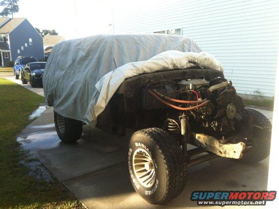 1979 Ford Bronco with tarp, front view, engine exposed, off-road tires