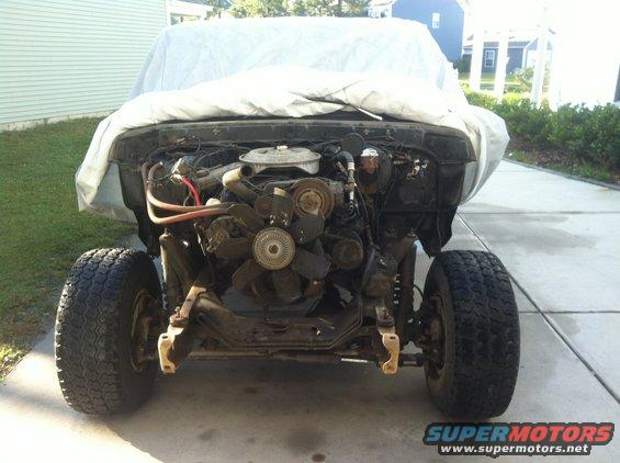 Vehicle engine bay with car cover, front tires visible