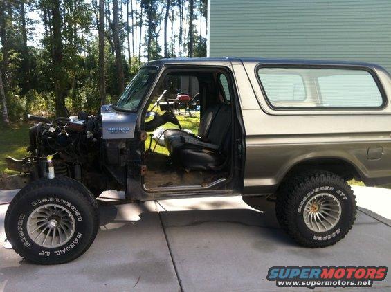 Side view of a Ford Bronco with its engine removed, driver's door open