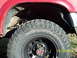1991 Toyota Pickup/SR5 - Close-up view of a red truck's fender and tire, showing the 'MOUNTAIN CAT' tire branding.