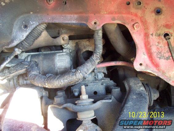 Close-up of engine bay with starter motor and hoses, red painted metal frame visible