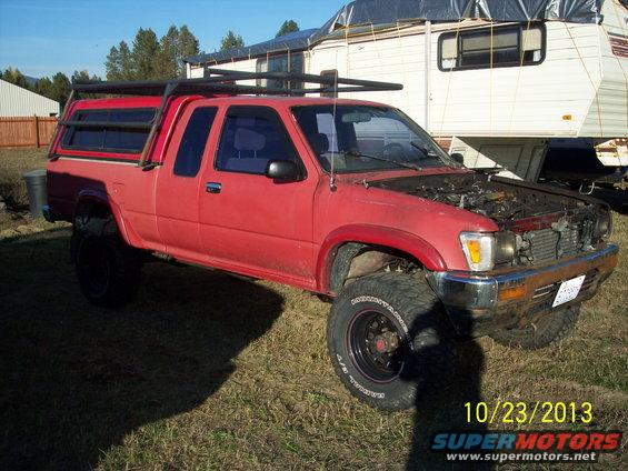 1991 Toyota Pickup/SR5 with camper shell, roof rack, and aftermarket wheels. Hood is open