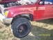 1991 Toyota Pickup/SR5 - A red pickup truck is shown from the front quarter angle with its hood open, revealing the engine compartment. The vehicle has off-road tir…