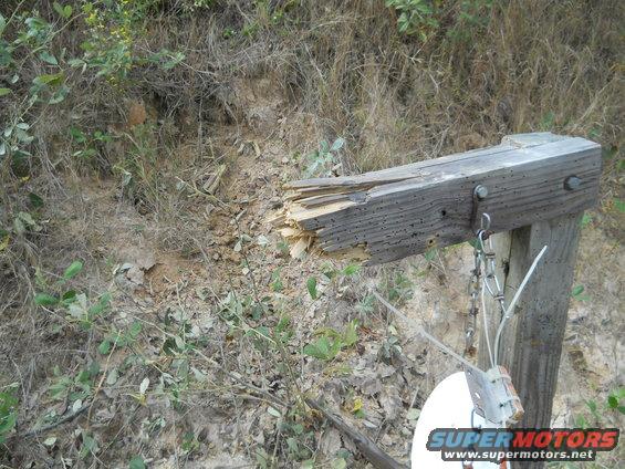 damaged wooden post with chain and white disc attached, outdoors