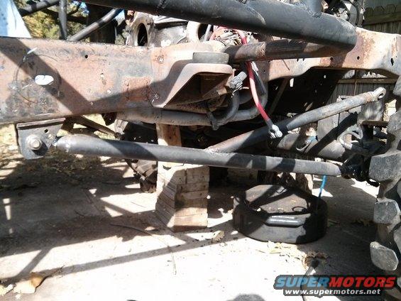 close-up of rusty vehicle frame with suspension components visible, vehicle is on blocks