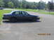 2003 Ford Crown Victoria - Side view of a dark 2003 Ford Crown Victoria sedan parked in a lot on a sunny day.
