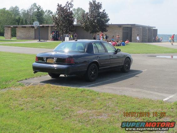 Black 2003 Ford Crown Victoria parked on asphalt with grass in foreground