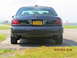 2003 Ford Crown Victoria - A dark sedan is parked outdoors near a body of water, with a person walking in the background.
