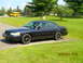 2003 Ford Crown Victoria - A dark blue 2003 Ford Crown Victoria sedan is parked on a driveway with a yellow school bus in the background.