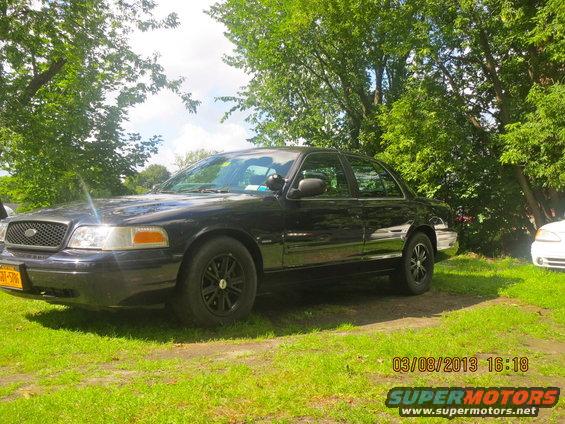Black 2003 Ford Crown Victoria parked on grass, front quarter view