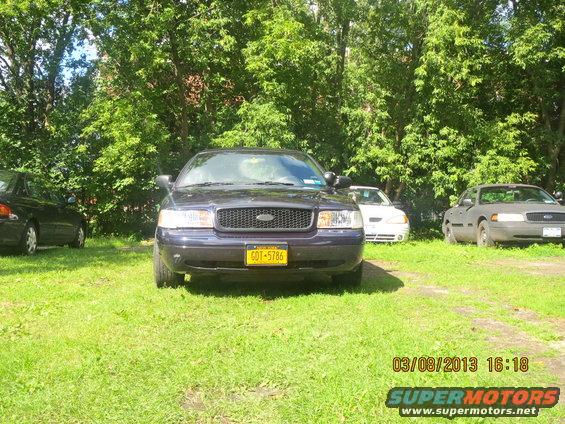 2003 Ford Crown Victoria front view, parked in grass with other cars. License plate 6DT-5786