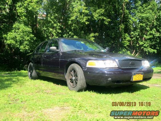 2003 Ford Crown Victoria parked on grass, front quarter view. Yellow license plate visible