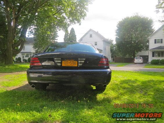 Black 2003 Ford Crown Victoria rear view parked on grass, New York license plate GDT-5786