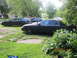2003 Ford Crown Victoria - Multiple black sedans, including a 2003 Ford Crown Victoria with a spotlight, are parked in a grassy area.