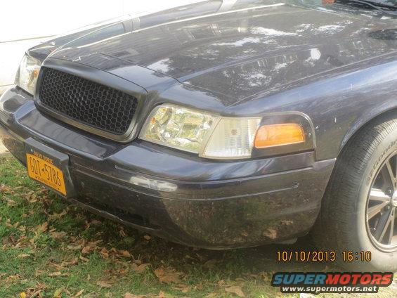 Front view of a dark 2003 Ford Crown Victoria with a black honeycomb grille and yellow New York license plate