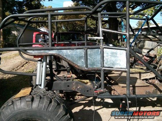 Custom off-road buggy frame with a red truck cab visible inside. Large tires and suspension components are present