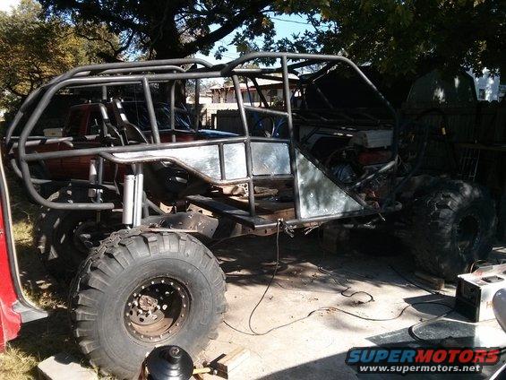 Custom off-road vehicle frame with large tires and roll cage, in a state of construction