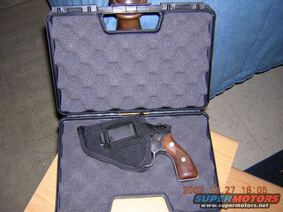 Revolver with wooden grip in a black foam-lined case, angled view