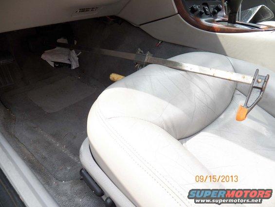 Car interior with light gray leather seats and a metal clamp resting on the passenger seat