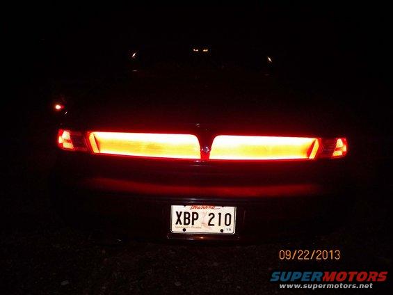 Car's rear light bar and license plate XBP 210 at night