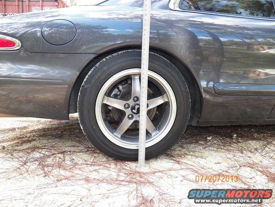 Dark gray coupe side view with ruler measuring ride height