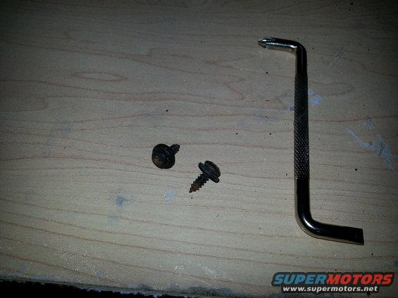 Two screws and a hex wrench on a wooden surface