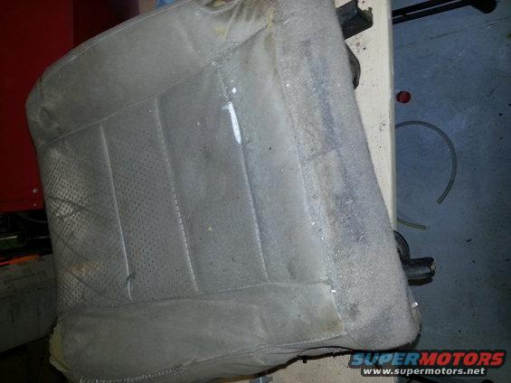 Close-up of a dirty, worn car seat with perforated fabric and stitching detail