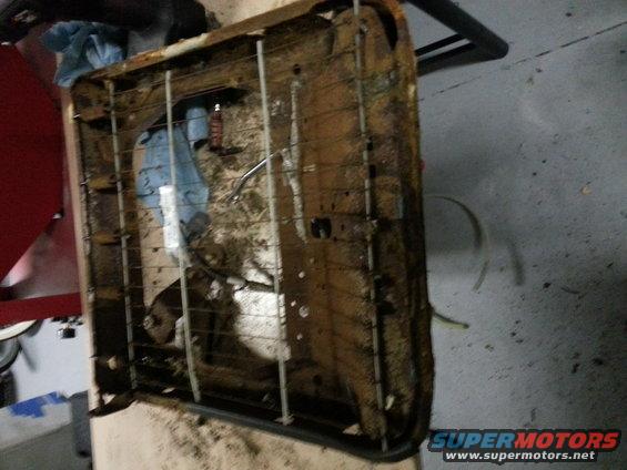 Rusty car seat frame with torn upholstery and visible springs