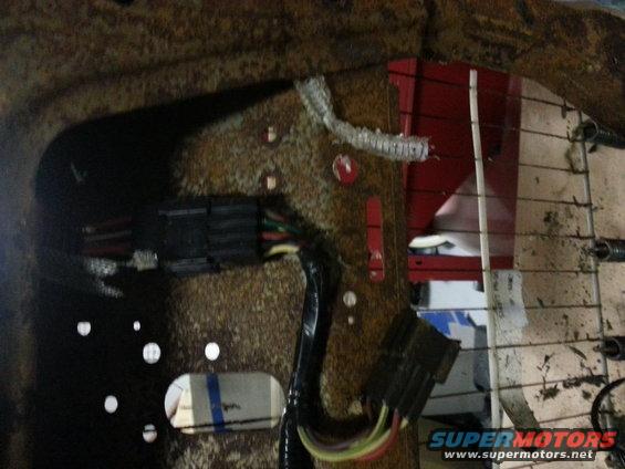 Close-up of car seat wiring and connectors. Some red plastic is visible behind the seat