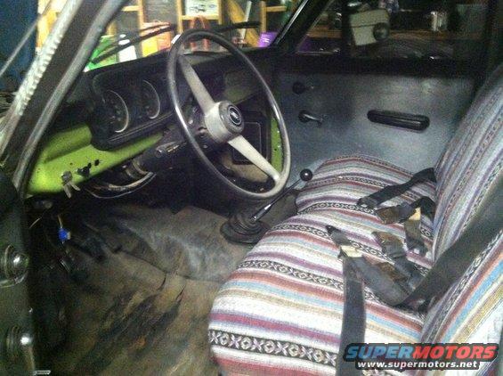Interior shot of a truck cab, showing the steering wheel, dashboard with gauges, and patterned seat covers