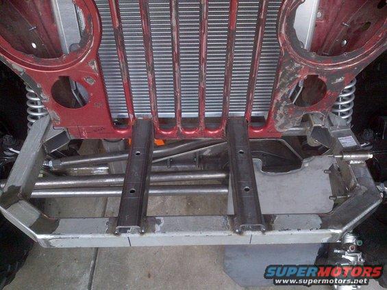 Jeep CJ-series chassis with red frame and silver grille components, viewed from below