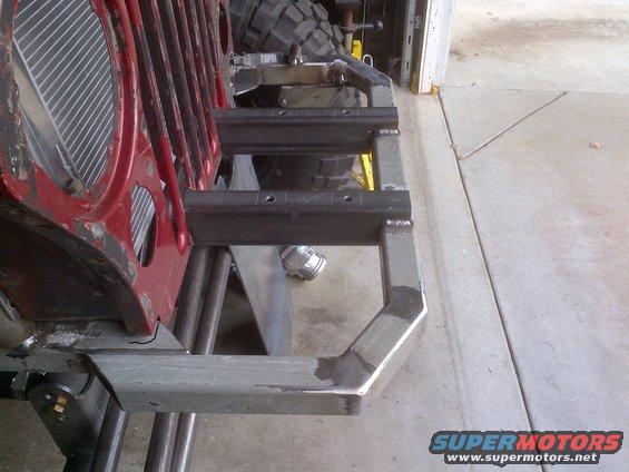 Red Jeep grille with custom metal bumper and suspension components visible